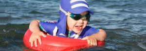Small boy in UV protective clothing and goggles floating on an inflatable circle.