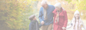 Family walking together outdoors, grandparents with grandchildren, with autumn leaves in the background.