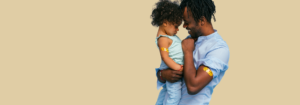 Man holding child after vaccination with band aids on their upper arms