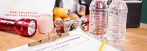 Emergency preparedness checklist with flashlight, water bottles and a first aid kit in the background