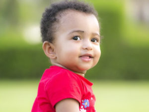 A smiling baby wearing a red shirt.
